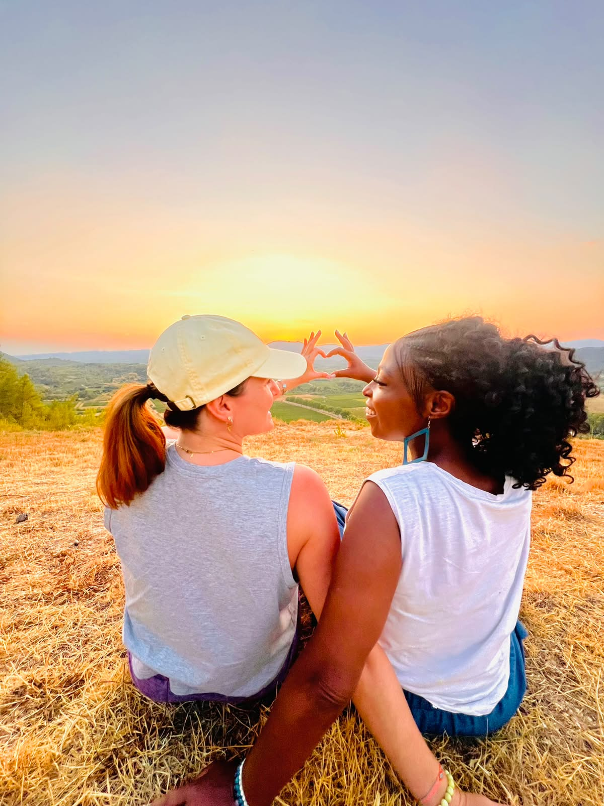 Le duo forme un cœur avec les mains face au coucher du soleil